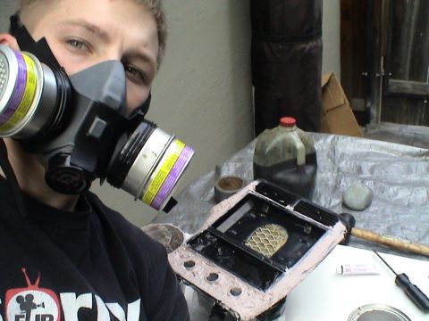 1997 Ford Probe - A person wearing a respirator works on a car's center console part, which is covered in putty.