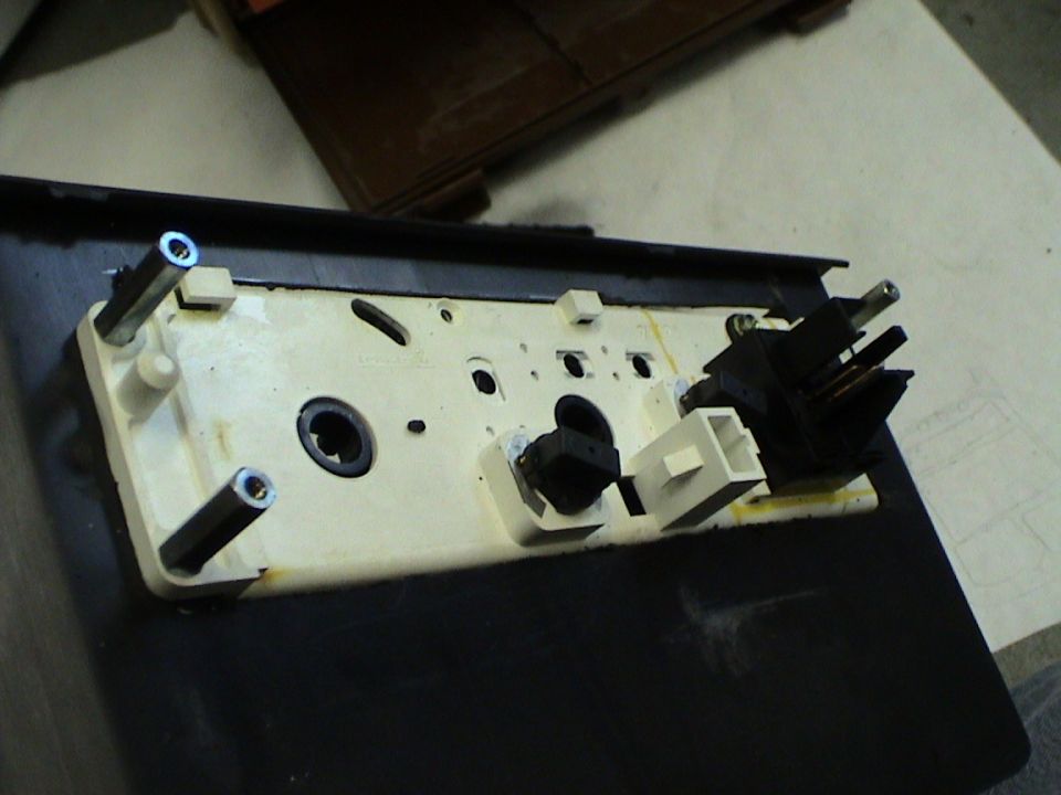 Back of a car's center console assembly with electrical connectors and mounting posts