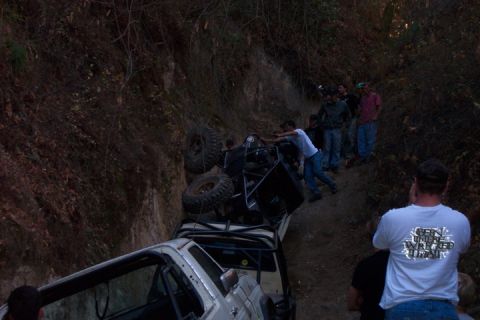 1989 Ford Bronco - Off-road vehicles stuck on a steep embankment with onlookers.