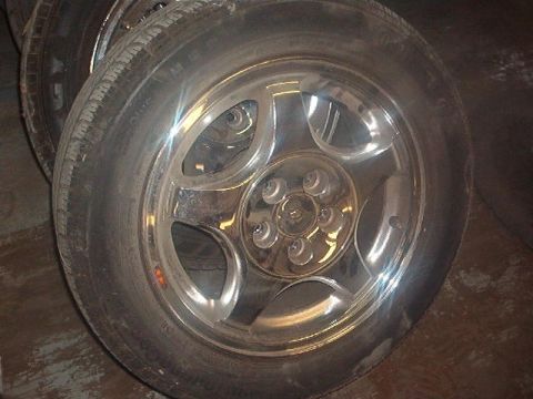 2000 Ford Taurus - A close-up view of a chrome wheel with a five-spoke design and a black tire.