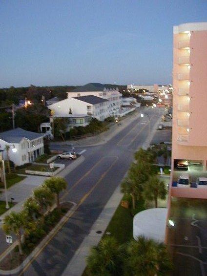 1994 Ford Probe - View of a street in a coastal town as dusk settles, with buildings and palm trees lining the road.
