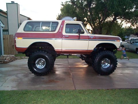 1979 Ford Bronco - Modified 1978 Ford Bronco on large tires, parked in a driveway with a child and another truck visible.