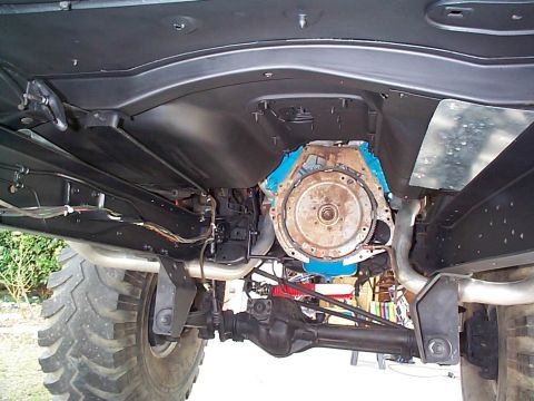 1979 Ford Bronco - Underside view reveals the engine, transmission, and drivetrain components of a vehicle, alongside its substantial tires.
