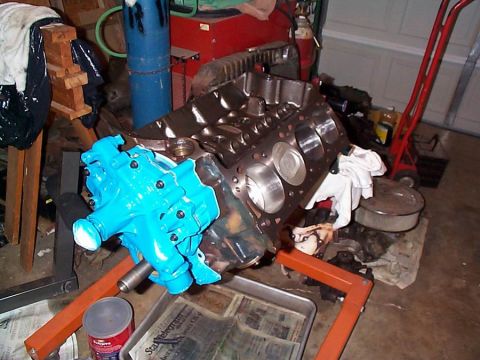 1979 Ford Bronco - Engine block and blue intake manifold on an engine stand in a garage setting.