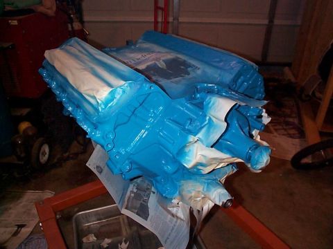 1979 Ford Bronco - An engine block is being prepped for painting with blue spray paint and masking materials.