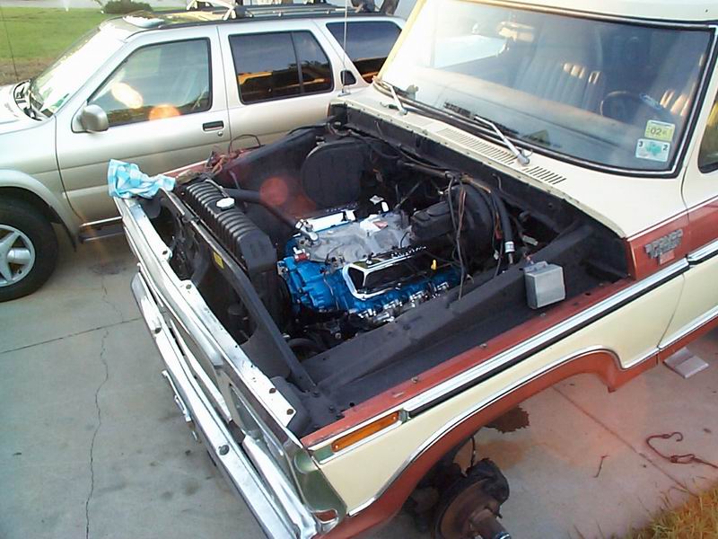 1979 Ford Bronco with hood open, showing a blue engine and missing front wheel