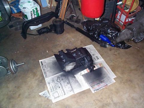 1979 Ford Bronco - An automotive part is being worked on in a garage setting, surrounded by other vehicle components.