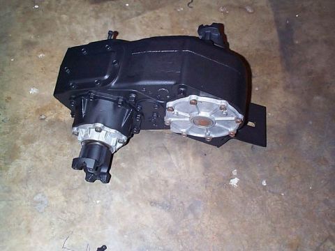 1979 Ford Bronco - This black transfer case features silver output flanges and is shown resting on a concrete surface.