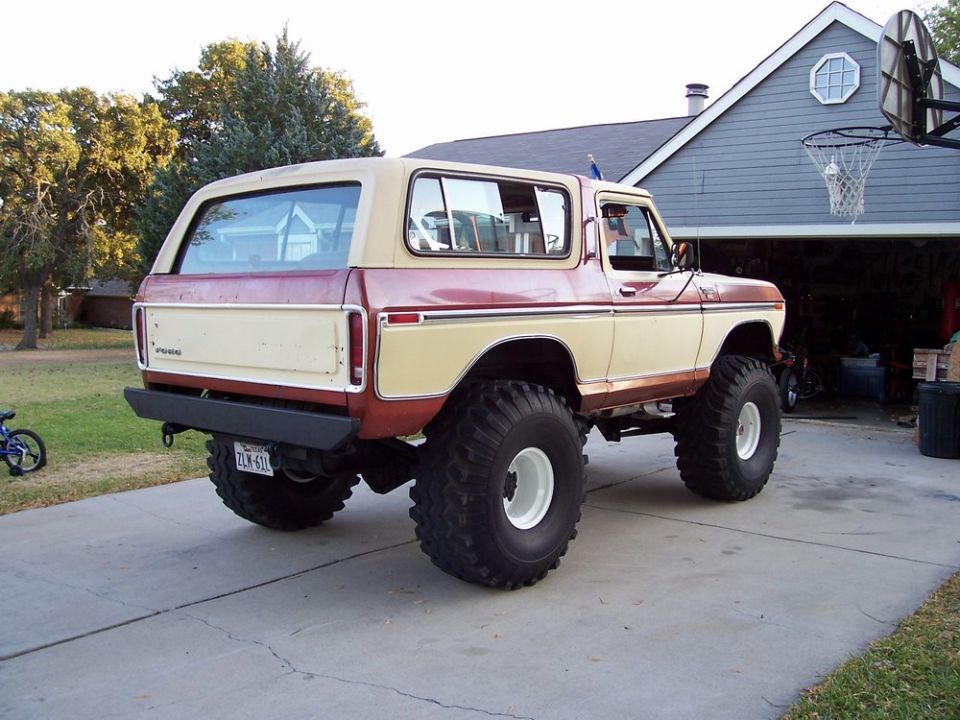 1979 Ford Bronco with large off-road tires and lifted suspension, parked in a driveway
