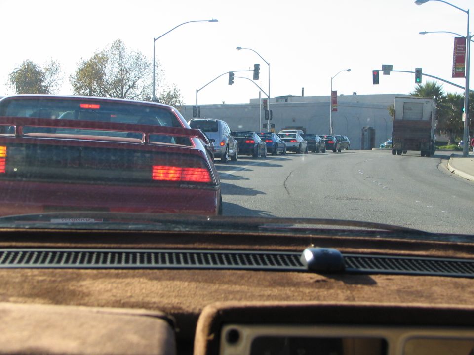 Red sports car with a spoiler and distinctive taillights in traffic