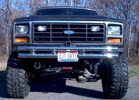 1986 Ford Bronco - Front view of a lifted black Ford truck with a chrome bumper and visible suspension components.
