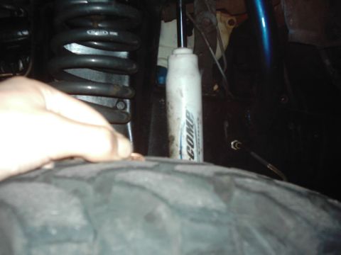 1978 Ford Bronco - A hand is shown near the tire, with suspension components visible in the background.