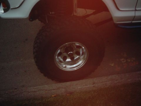 1978 Ford Bronco - Close-up of a large off-road tire and chrome wheel on a lifted vehicle.