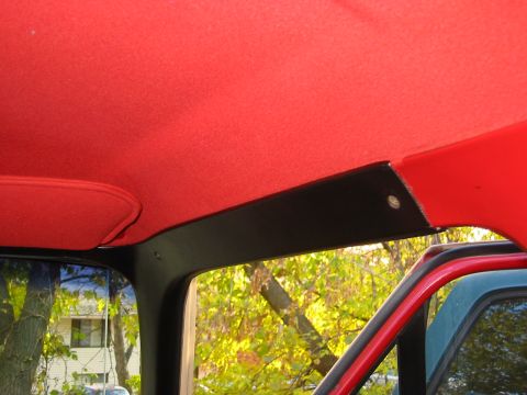 1990 Ford Bronco - Interior view of a vehicle a red headliner and black trim, with another vehicle visible through the window.