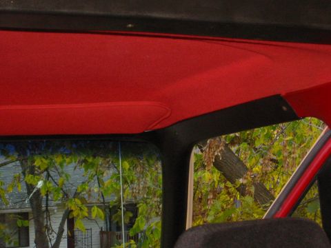 1990 Ford Bronco - View from inside a vehicle shows a red headliner and a window looking out onto a residential scene.