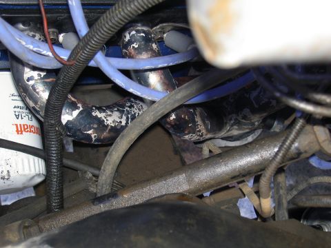 1988 Ford Bronco - Close-up of an engine's exhaust manifold and associated wiring, with an oil filter visible.