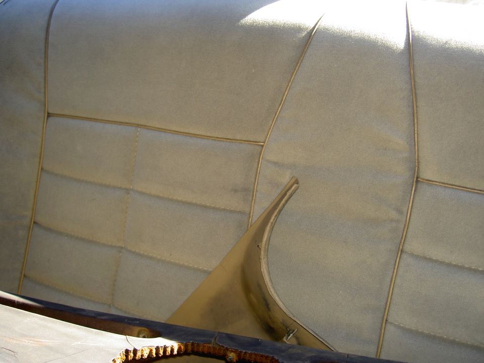 Tan interior rear seat with stitching detail and a curved plastic trim piece