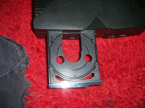 1997 Ford Probe - Gaming console with its CD tray extended, resting on a textured red surface.