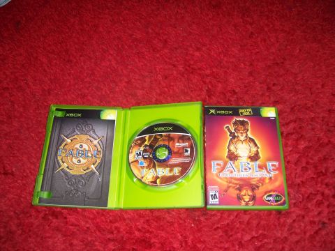 1997 Ford Probe - The Xbox game Fable is shown in its open case with the disc and manual, alongside the closed game case.