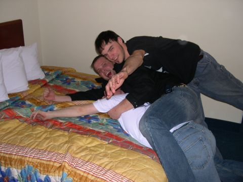 1997 Ford Probe - Three men are playfully wrestling on a bed in a hotel room, with a SuperMotors logo visible in the lower right corner.