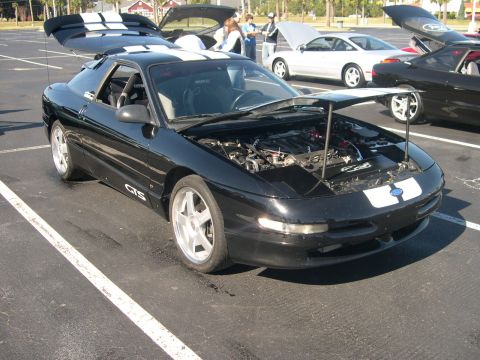 1997 Ford Probe - Black 1997 Ford Probe with racing stripes and open hood at a car meet.