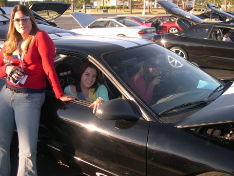 1997 Ford Probe - Two women pose with a black 1997 Ford Probe at an outdoor car show.