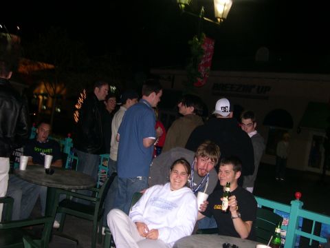 1997 Ford Probe - People are gathered outdoors at night, with some seated at tables and others standing around.