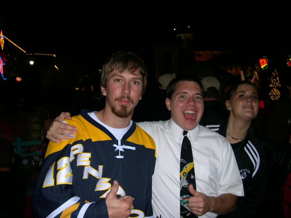 Three people pose for a photo at night with blurry lights in the background