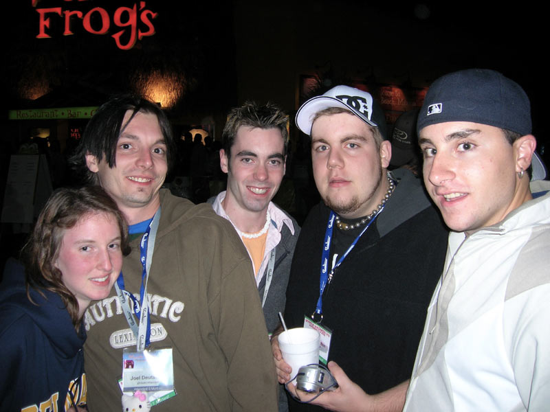 Five people posing for a photo in front of a sign that says "Frog's". They are wearing lanyards