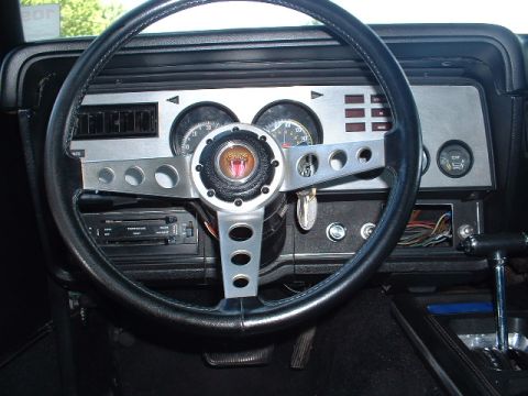 1978 Ford Mustang II - The interior of a 1978 Ford Mustang II Cobra II shows a dashboard with gauges and a steering wheel a snake emblem.