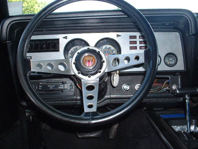 1978 Ford Mustang II Cobra II interior with a black steering wheel, silver dashboard accents, and a snake emblem on the horn