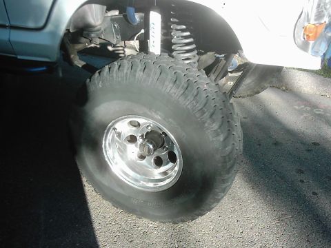 1978 Ford Bronco - Detail shot of off-road suspension and tire, with partial text on the shock absorber.