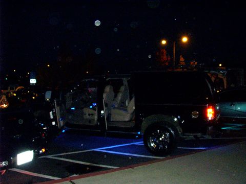 2000 Ford Excursion - A black SUV is parked at night with its doors open, revealing blue underglow lighting.