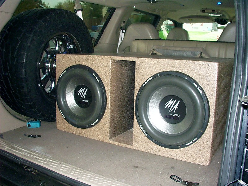 Dual MA Audio subwoofer box in SUV cargo area with spare tire and tan interior
