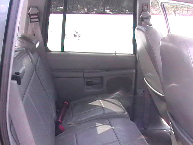 Back seats and door panel of a vehicle. A pink object is on the seat