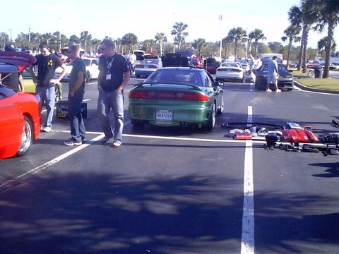 1995 Ford Probe - A green coupe is parked in a lot with several other vehicles and people milling about.