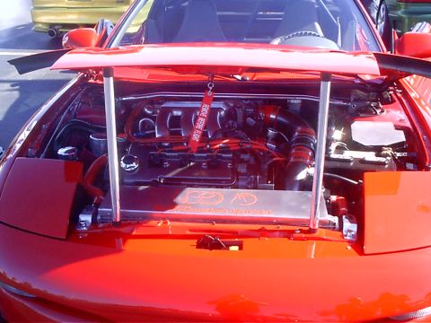 1995 Ford Probe - Engine bay of a red sports car, with the hood open, revealing the engine and various components.