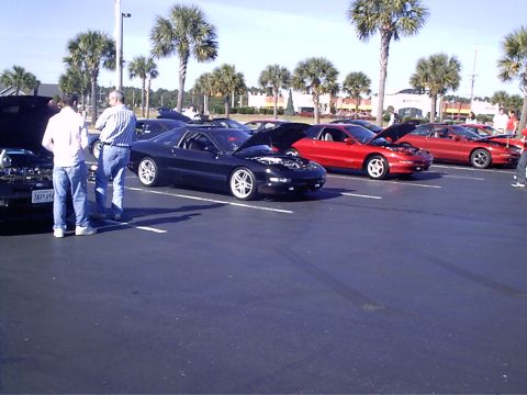 1995 Ford Probe - A black 1995 Ford Probe is displayed with its hood open, alongside other vehicles in a parking lot.