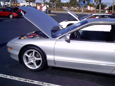1995 Ford Probe - A silver 1995 Ford Probe is parked with its hood up at an outdoor event, alongside other vehicles.