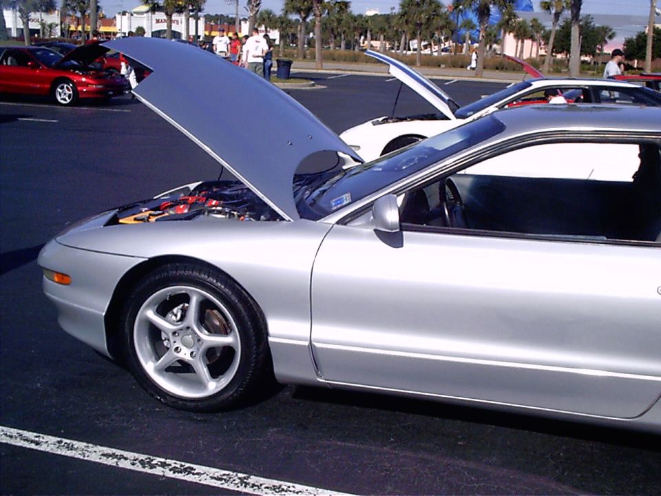 Silver 1995 Ford Probe with hood open, parked next to a white car with hood open. Another red car is visible in the background