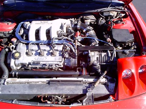 1995 Ford Probe - The engine bay of a red 1995 Ford Probe is shown, highlighting the V6 engine and associated components.