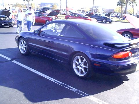 1995 Ford Probe - A blue 1995 Ford Probe is parked in a lot, with other vehicles visible in the background.