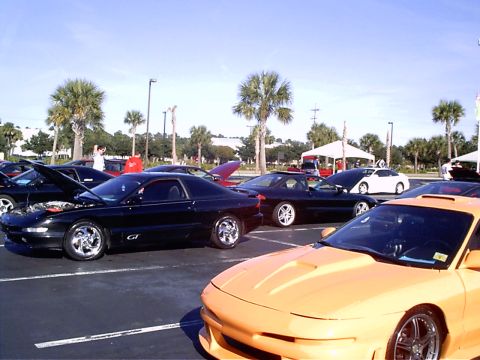 1995 Ford Probe - A black 1995 Ford Probe GT is parked with its hood open, alongside other vehicles under a sunny sky.