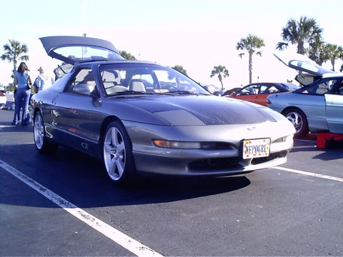 1995 Ford Probe - A gray 1995 Ford Probe is parked with its hood and trunk open, alongside other vehicles.