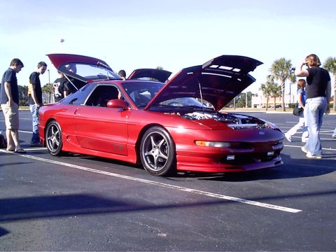 1995 Ford Probe - A red 1995 Ford Probe is displayed with its hoods open, attracting attention from onlookers.