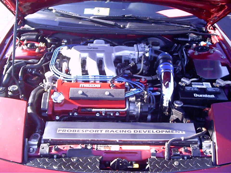 Red engine bay with V6 intake manifold, red valve covers, and "PROBESPORT RACING DEVELOPMENT" plate