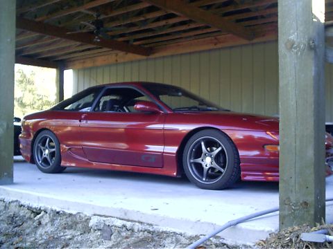 1995 Ford Probe - A red 1995 Ford Probe GT coupe is parked under a covered structure.