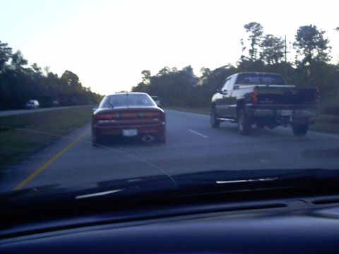 1995 Ford Probe - Two vehicles travel down a highway under a hazy sky.