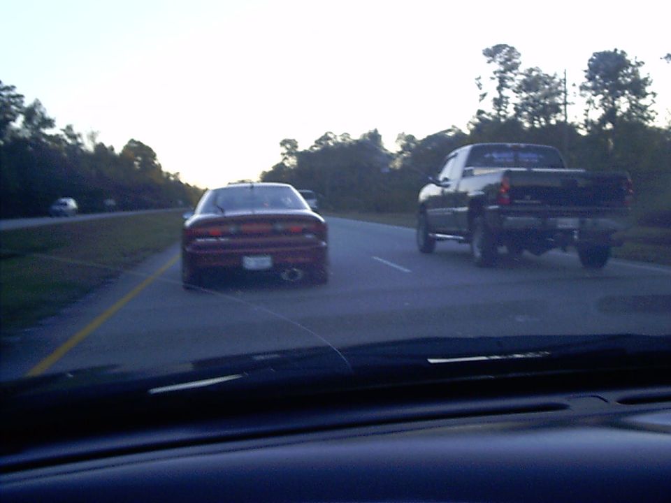 Red sports car and black pickup truck driving on a highway