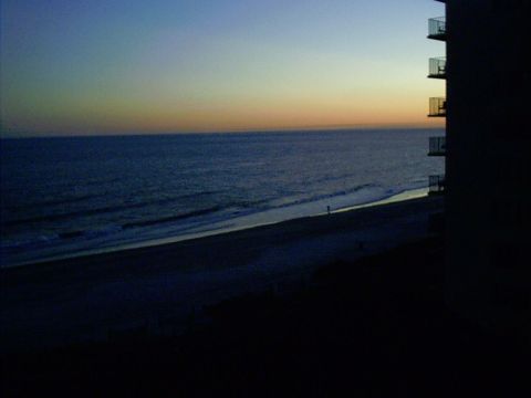 1995 Ford Probe - A solitary figure walks on the beach as the sun sets over the ocean.